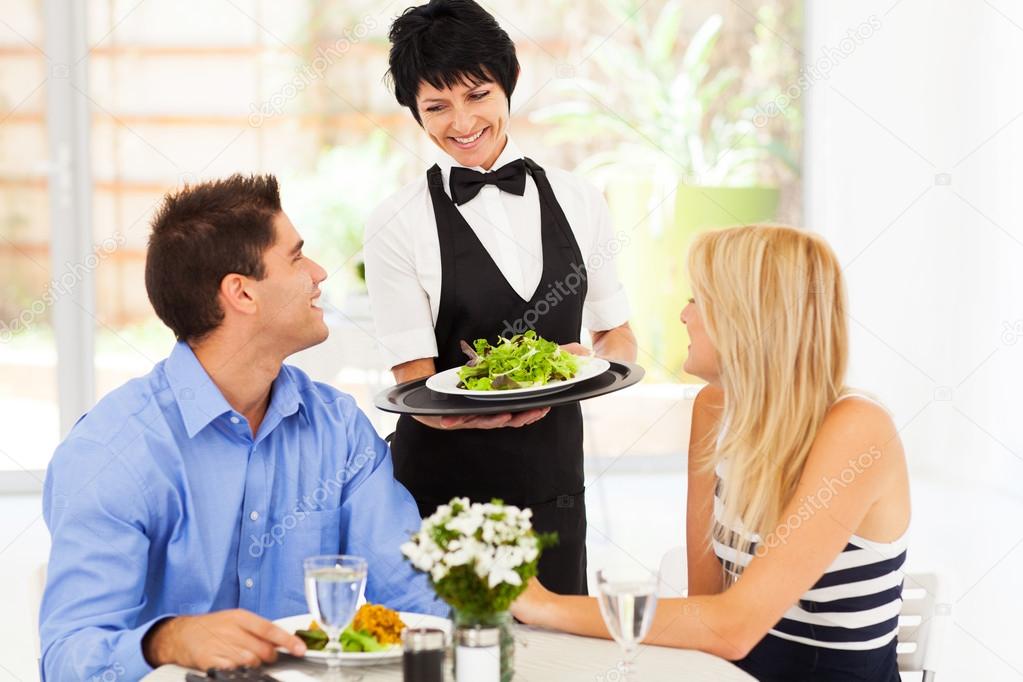 Happy waitress serving customers in restaurant