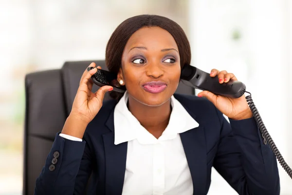 Funny mujer afroamericana trabajadora de oficina hablando por teléfono fijo y móvil al mismo tiempo —  Fotos de Stock
