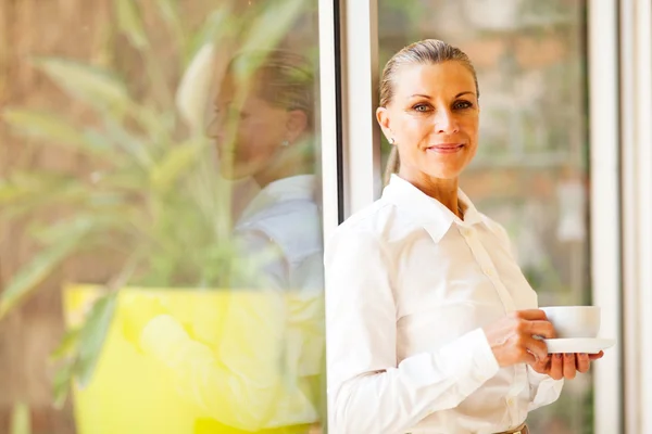 Pretty senior female corporate executive in office with coffee — Stock Photo, Image