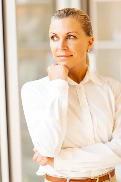 Pensativo feminino sênior escritório trabalhador olhando para fora janela — Fotografia de Stock