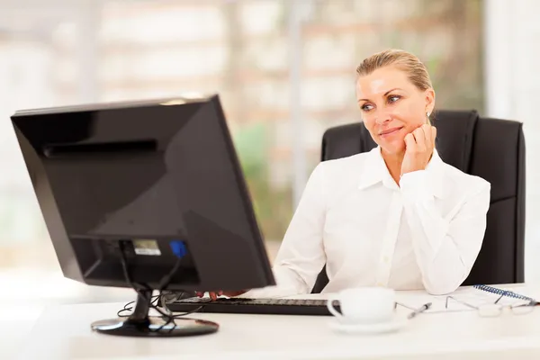 Thoughtful senior businesswoman in front of computer — Stock Photo, Image