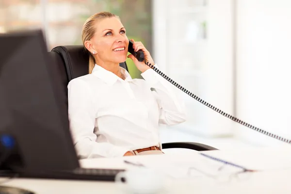 Midden leeftijd zakenvrouw praten over de telefoon in office — Stockfoto