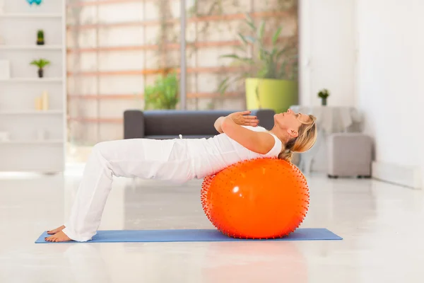 Mature woman working out with exercise ball at home — Stock Photo, Image