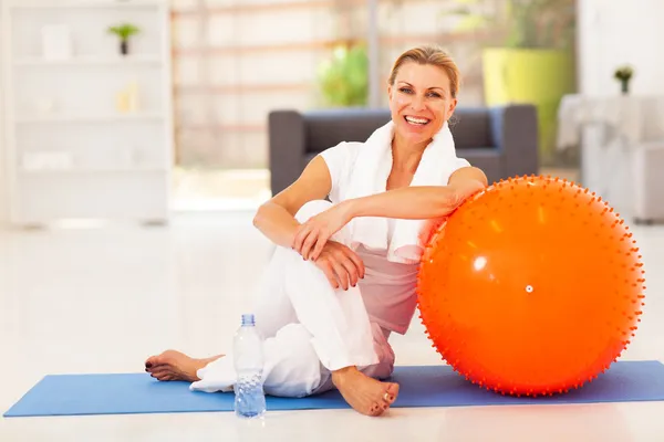 Heureuse femme âgée reposant sur le tapis après l'exercice à la maison — Photo