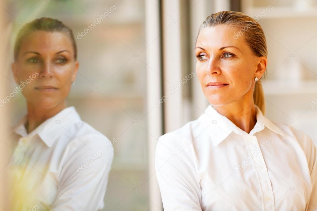 Elegant middle aged businesswoman standing by office window