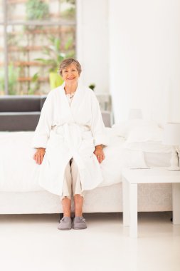 pijamaları yatağın üstüne oturan mutlu yaşlı kadın