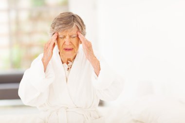 Senior woman feeling headache at home clipart