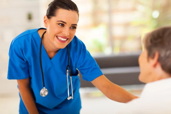 Amigável jovem enfermeira conversando com paciente sênior no hospital — Fotografia de Stock