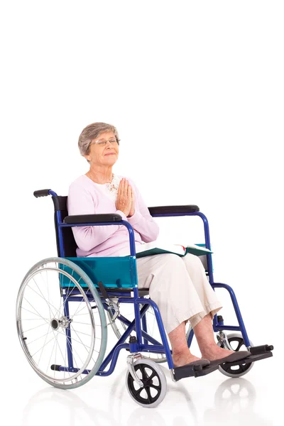 Femme âgée assise en fauteuil roulant et priant isolée sur du blanc — Photo