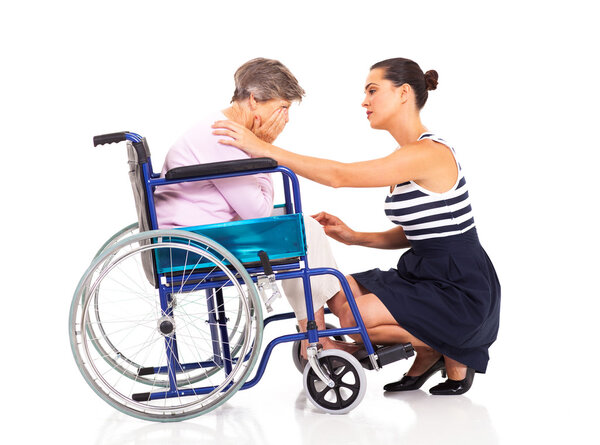 Young woman comforting disabled senior mother on white