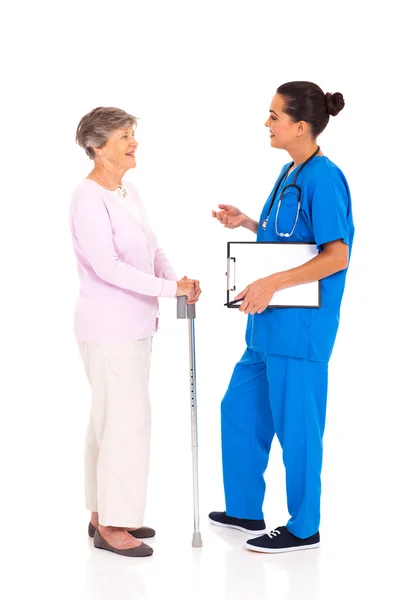 Krankenschwester im Gespräch mit Seniorin isoliert auf weiß — Stockfoto