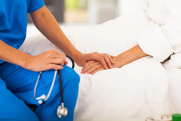 Médico sosteniendo las manos del paciente mayor y consolándola — Foto de Stock