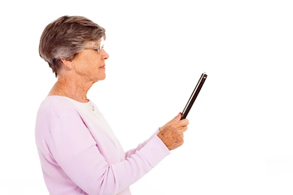 Elderly woman reading book on tablet computer isolated on white — Stock Photo, Image