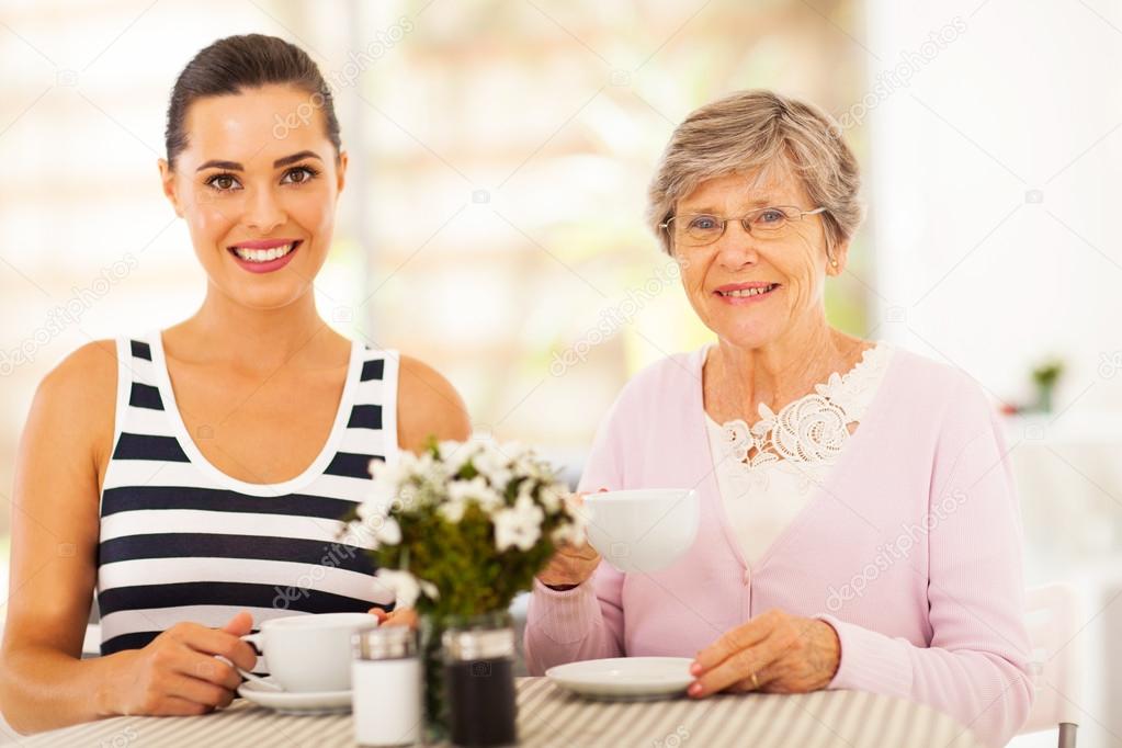 Beautiful young woman having tea with grandmother or mother