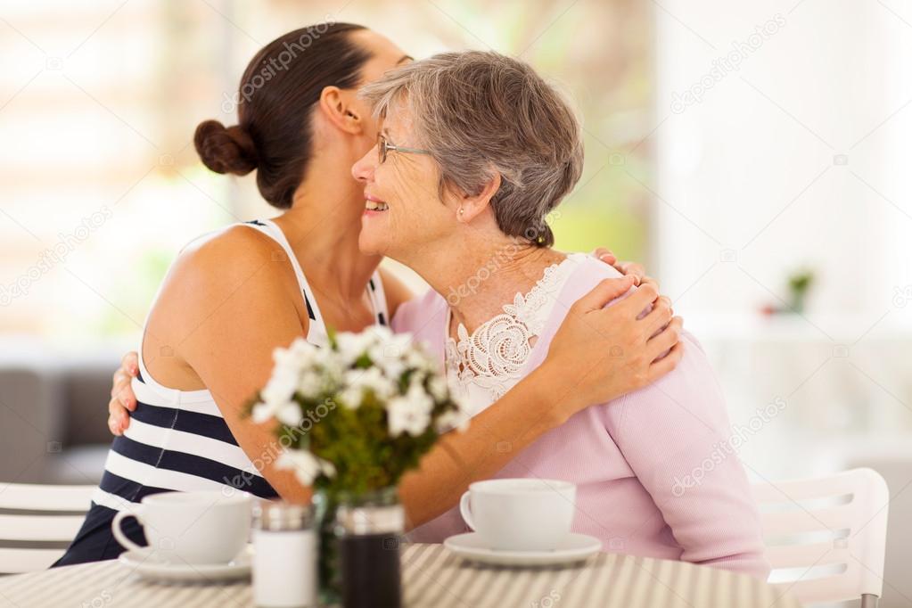 Young woman hugging senior mother when visiting her