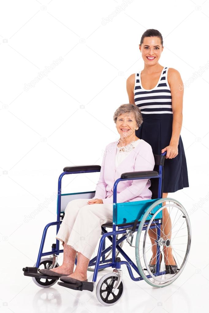 Caring daughter pushing senior mother on wheelchair on white background