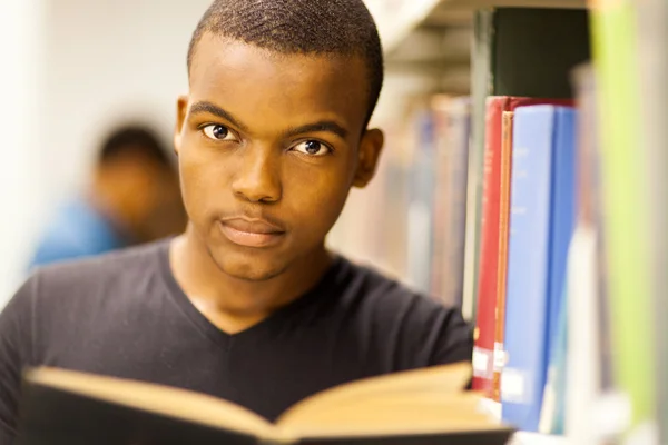 Maschio africano americano studente universitario lettura in biblioteca — Foto Stock