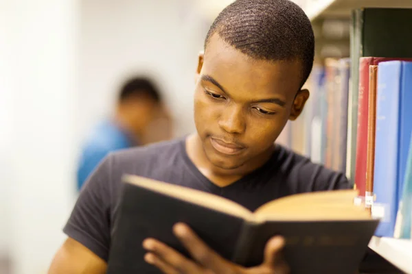 Männliche afrikanische Universitätsstudentin liest in Bibliothek — Stockfoto