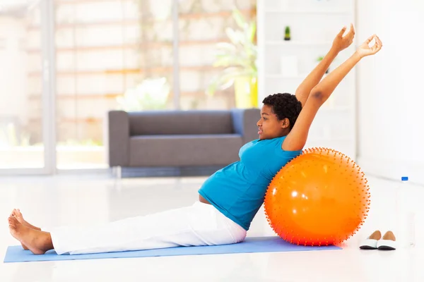 Mujer afroamericana embarazada haciendo ejercicio en el suelo en casa —  Fotos de Stock