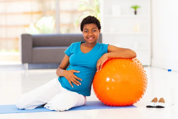 Donna africana americana incinta con palla da ginnastica a casa — Foto Stock