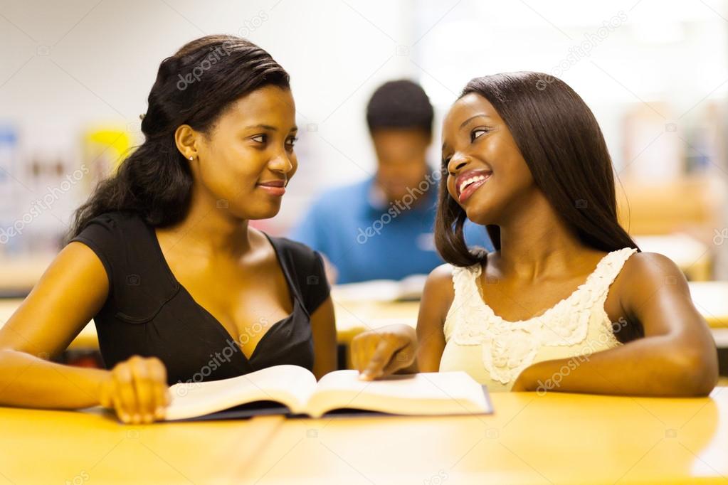 two african college girls reading book in library