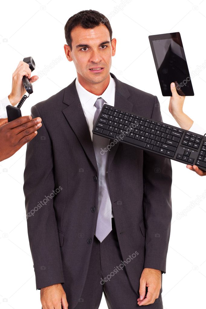 tired male office worker with multiple gadgets around him