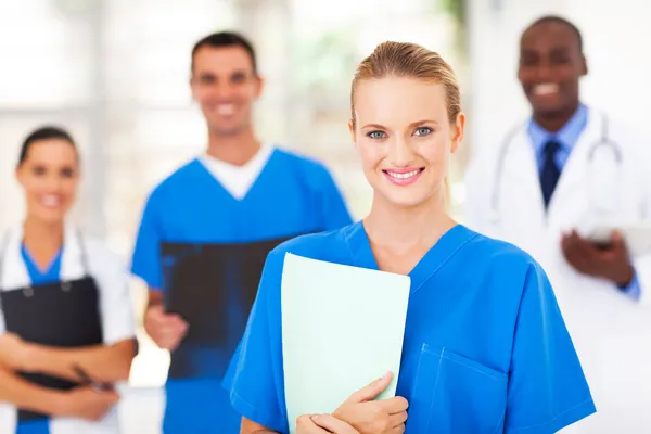 Красивая медицинская сестра и коллеги в больнице — стоковое фото
