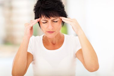 Woman having headache and massaging forehead clipart