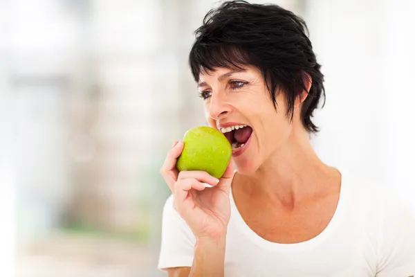 Frau isst einen grünen Apfel — Stockfoto