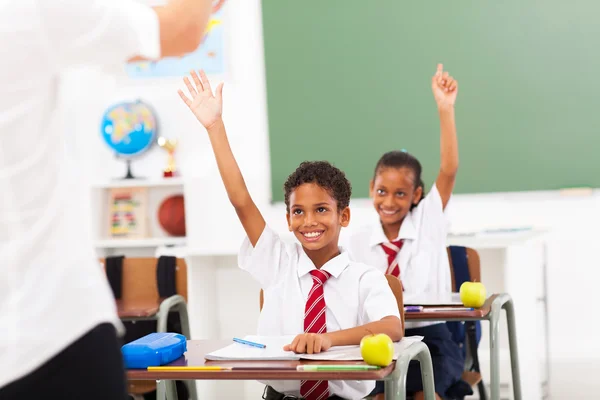 Elementary school students arms up in classroom — Zdjęcie stockowe