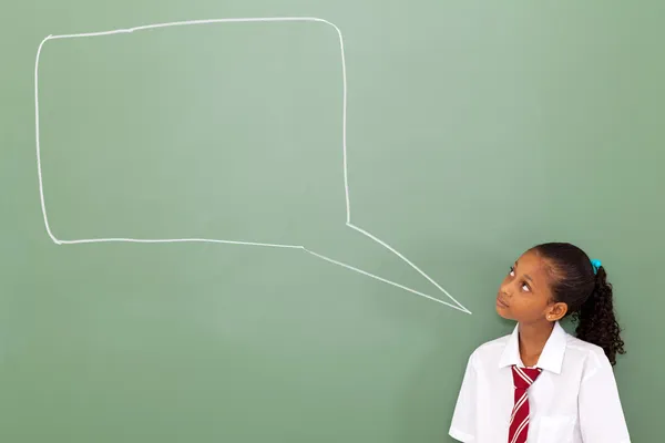 Colegiala primaria mirando la caja de chat dibujado en pizarra —  Fotos de Stock