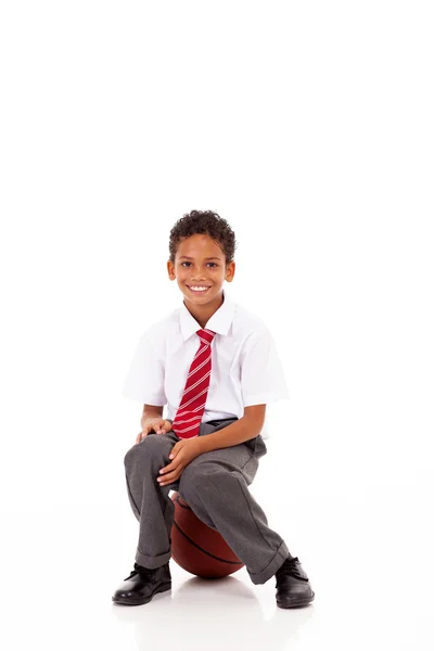 Lindo colegial de primaria sentado en la pelota de la cesta en blanco — Foto de Stock