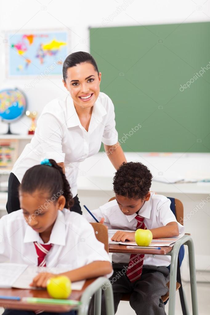 Beautiful elementary school teacher in classroom with students