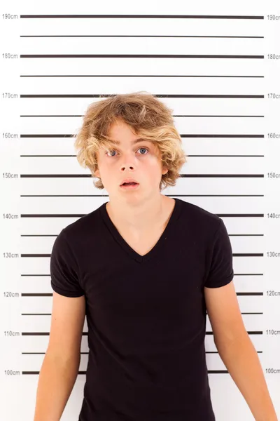 Shocked teen boy taking police mug shot — Stock Photo, Image