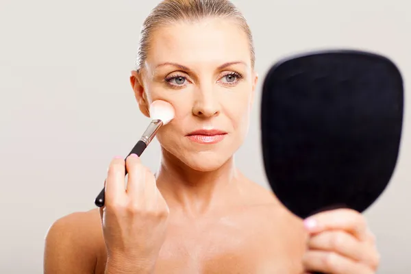 Mulher de meia idade aplicando maquiagem — Fotografia de Stock