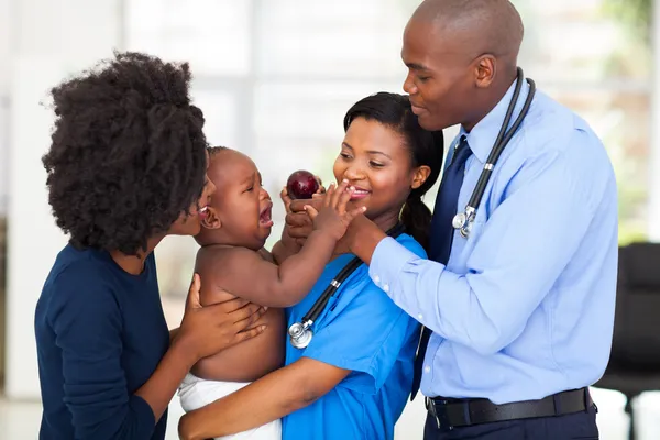 Дружелюбная медсестра, держащая плачущего ребенка — стоковое фото