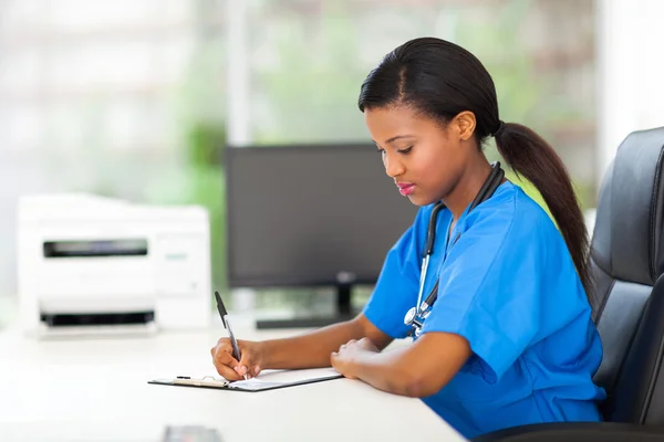 Kvinnliga barnsjuksköterska skriva medicinska rapporter — Stockfoto