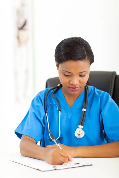 Mujer africana practicante médica escribir informe médico — Foto de Stock