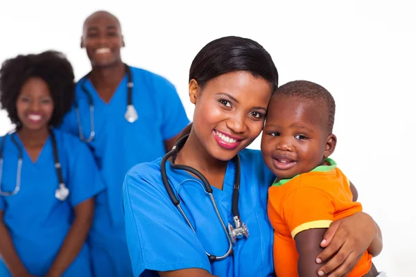 黑色的儿科医生和与同事在背景上的小男孩 — 图库照片