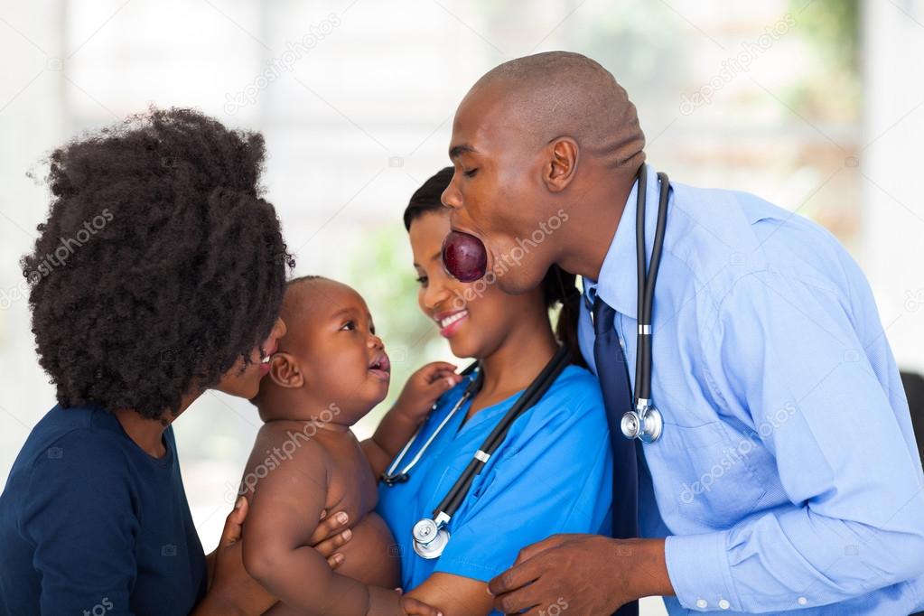 funny african male doctor cheering up sick baby
