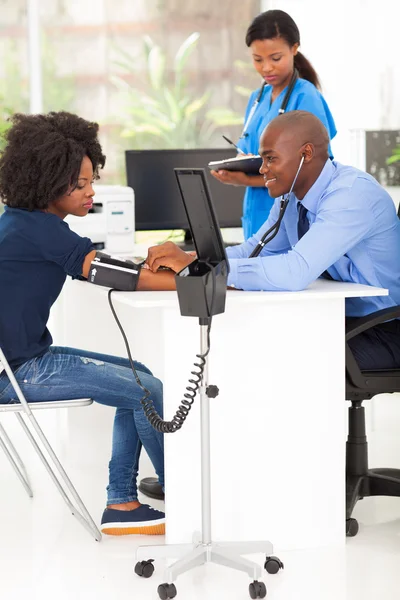 Африканский врач измеряет кровяное давление пациента — стоковое фото