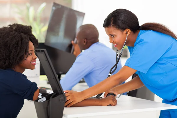 Enfermeira médica africana medindo a pressão arterial do paciente — Fotografia de Stock