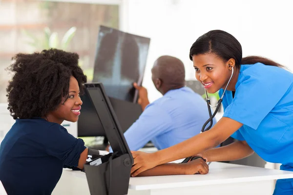 Enfermera africana comprobando la presión arterial del paciente — Foto de Stock