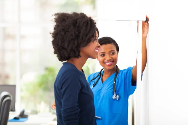 Африканская медсестра, измеряющая рост пациента — стоковое фото