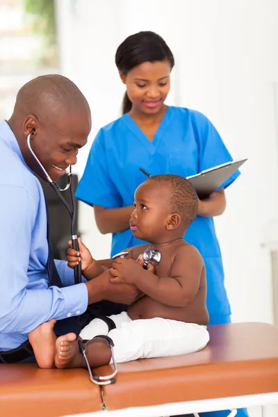 Милый африканский маленький пациент тянет доктора стетоскоп — стоковое фото