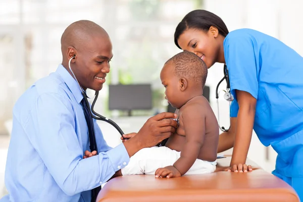 Male pediatric doctor examining baby boy with female nurse — Stock Photo, Image