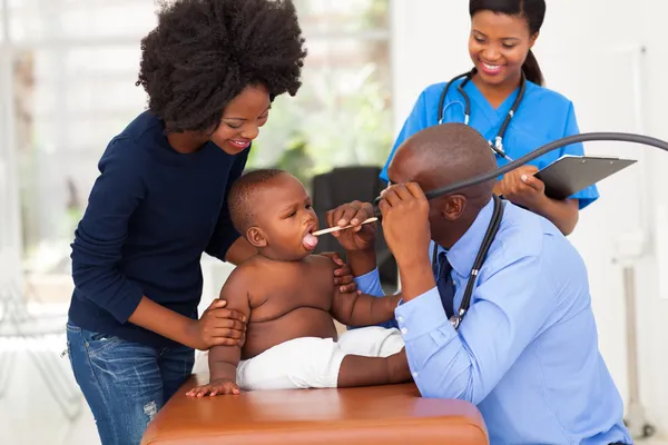 Maschio africano medico esaminando bambino — Foto Stock