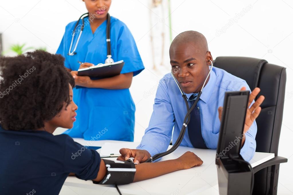 african general practitioner checking patient's blood pressure