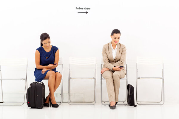 претенденты, играющие со своими мобильными телефонами перед собеседованием
