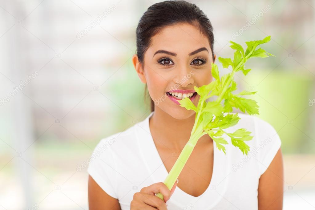 female vegetarian biting celery's leaves